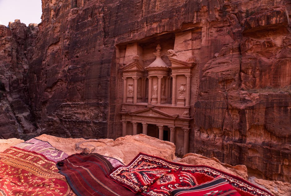 The iconic Treasury in Petra, Jordan with vibrant handmade rugs in the foreground.